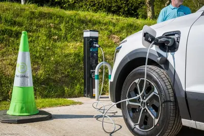 a car is plugged into a charging station next to a green cone at Water Mill at East Trenean Farm -Luxury Cornish Cottage sleeping 4 with hot tub, private garden, rural views and EV facilities in East Looe