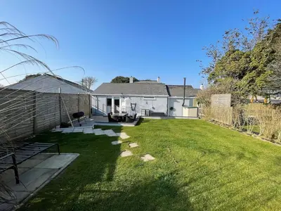 a backyard with a lawn and a house at The Cottage, Cox Hill House, Cox Hill, Chacewater, TR4 8LY in Truro