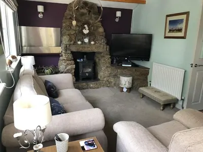a living room with a couch and a stone fireplace at The Cottage, Cox Hill House, Cox Hill, Chacewater, TR4 8LY in Truro