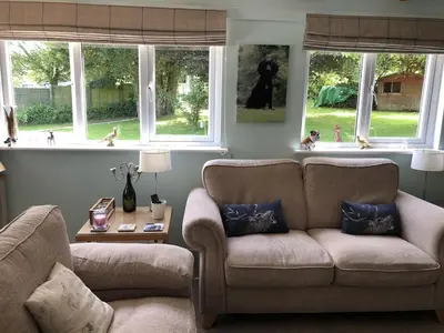a living room with a couch and a chair and windows at The Cottage, Cox Hill House, Cox Hill, Chacewater, TR4 8LY in Truro