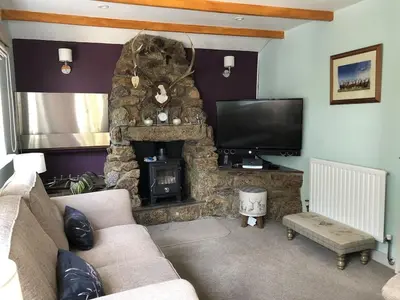 a living room with a stone fireplace and a television at The Cottage, Cox Hill House, Cox Hill, Chacewater, TR4 8LY in Truro