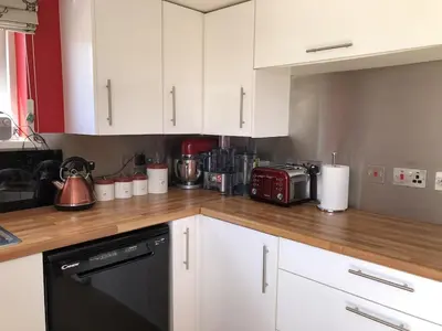 a kitchen with white cabinets and a black dishwasher at The Cottage, Cox Hill House, Cox Hill, Chacewater, TR4 8LY in Truro