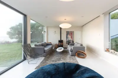 a living room with a couch and chairs and large windows at Footsteps from the beach - Hot tub - Cosy fireplace in Praa Sands