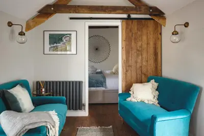 a living room with two blue chairs and a mirror at Seascape Hideaways at Port Isaac in Port Isaac