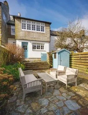 a patio with three benches and a table and a house at Seascape Hideaways at Port Isaac in Port Isaac