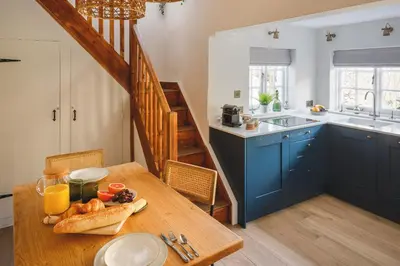 a kitchen with a wooden table and blue cabinets at Seascape Hideaways at Port Isaac in Port Isaac