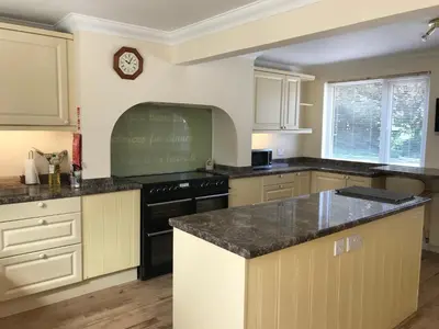 a kitchen with white cabinets and a clock on the wall at Large Family House - sleeps 10. Central Location. 15 mins from coast. in Truro