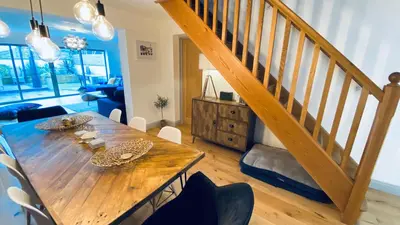 a dining room with a wooden table and a staircase at Tregenna House - St Ives, A Beautiful Newly Refurbished 4 Bedroom Family Town House With Alfresco Dining Garden and Private Parking Spaces in St Ives