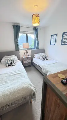 a bedroom with two beds and a table and a window at Tregenna House - St Ives, A Beautiful Newly Refurbished 4 Bedroom Family Town House With Alfresco Dining Garden and Private Parking Spaces in St Ives
