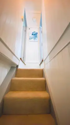 a staircase in a building with orange carpet and a window at SPINDRIFT is A Beautiful Newly Refurbished THREE BEDROOM Private Family House located on the OLD HARBOUR and the COASTAL PATH in the Heart of Beautiful POLPERRO in Polperro