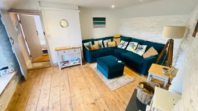 a living room with a blue couch and wooden floors at SPINDRIFT is A Beautiful Newly Refurbished THREE BEDROOM Private Family House located on the OLD HARBOUR and the COASTAL PATH in the Heart of Beautiful POLPERRO in Polperro