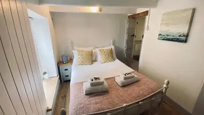 a bedroom with a bed with two towels on it at SPINDRIFT is A Beautiful Newly Refurbished THREE BEDROOM Private Family House located on the OLD HARBOUR and the COASTAL PATH in the Heart of Beautiful POLPERRO in Polperro