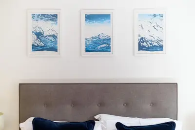 a bed in a room with three pictures on the wall at Trewhiddle 40 - A Luxury Cottage by Together Travel in St Austell