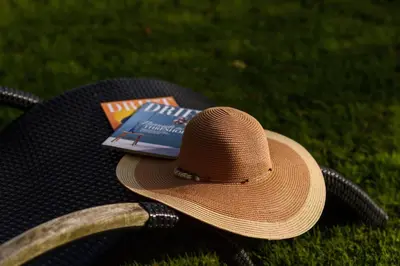 a straw hat and a book sitting on the grass at Trewhiddle 40 - A Luxury Cottage by Together Travel in St Austell