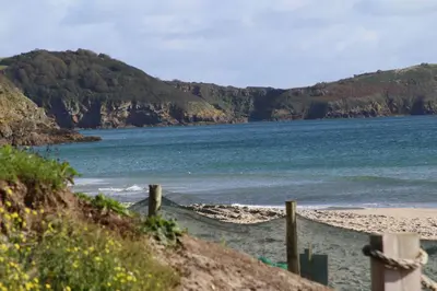 a beach with a fence and the ocean at Trewhiddle 40 - A Luxury Cottage by Together Travel in St Austell