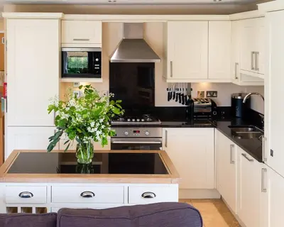 a kitchen with white cabinets and a vase of flowers at Trewhiddle Retreat V8 by Together Travel - Luxury 3-Bedroom Villa in St Austell