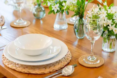 a table with plates and bowls on a wooden table at Trewhiddle Retreat V8 by Together Travel - Luxury 3-Bedroom Villa in St Austell