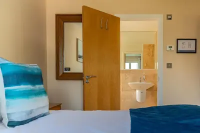 a bedroom with a bed and a sink and a door at Trewhiddle Retreat V8 by Together Travel - Luxury 3-Bedroom Villa in St Austell