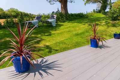 two blue pots with plants on a wooden deck at Trewhiddle Retreat V8 by Together Travel - Luxury 3-Bedroom Villa in St Austell