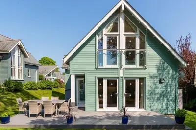 a green house with a table and chairs at Trewhiddle Retreat V8 by Together Travel - Luxury 3-Bedroom Villa in St Austell