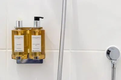 a bottle of oil hanging on a wall in a bathroom at Trewhiddle Retreat V8 by Together Travel - Luxury 3-Bedroom Villa in St Austell