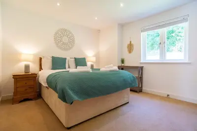 a bedroom with a large bed and a window at Trewhiddle Retreat V4 by Together Travel - Luxury 4-Bedroom Villa in St Austell