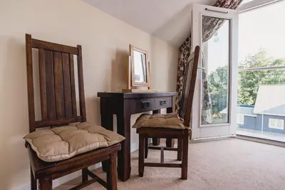 a room with a chair and a desk and a window at Trewhiddle Retreat V31 by Together Travel - Luxury 3-Bedroom Villa in St Austell