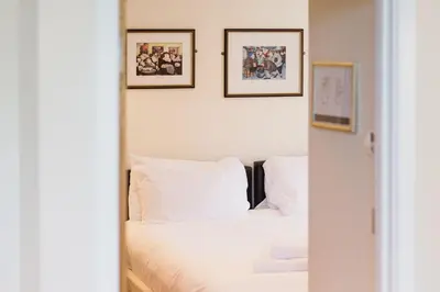 a bedroom with a white bed with three pictures on the wall at Trewhiddle Retreat V31 by Together Travel - Luxury 3-Bedroom Villa in St Austell