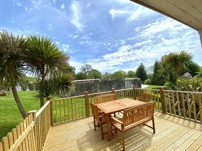 a wooden deck with a table and chairs on it at Trewhiddle Retreat V31 by Together Travel - Luxury 3-Bedroom Villa in St Austell