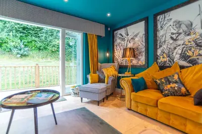 a living room with a yellow couch and a table at Trewhiddle Retreat V3 by Together Travel - Luxury 4-Bedroom Villa in St Austell