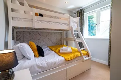 a bedroom with bunk beds with yellow towels and a lamp at Trewhiddle Retreat V3 by Together Travel - Luxury 4-Bedroom Villa in St Austell