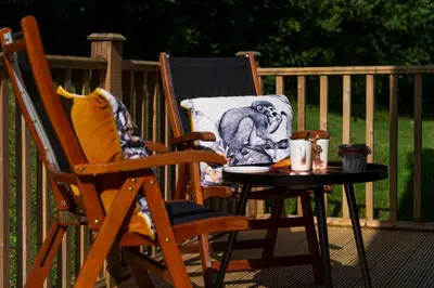 a chair and a table with a pillow on a porch at Trewhiddle Retreat V3 by Together Travel - Luxury 4-Bedroom Villa in St Austell