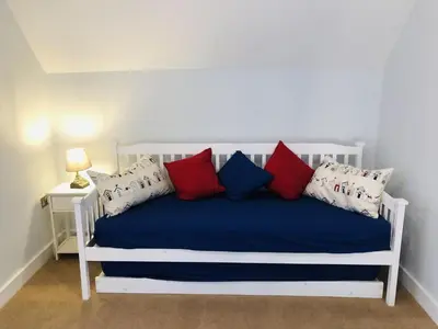 a white bed with red and blue pillows on it at Trewhiddle Retreat V29 by Together Travel - Luxury 4-Bedroom Villa in St Austell