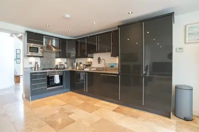 a large kitchen with black cabinets and a tile floor at Trewhiddle Retreat V25 by Together Travel - Luxury 4-Bedroom Villa in St Austell