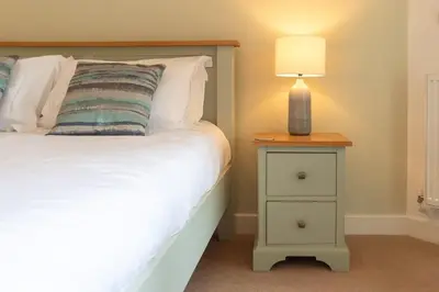 a bedroom with a bed and a nightstand with a lamp at Trewhiddle Retreat V25 by Together Travel - Luxury 4-Bedroom Villa in St Austell