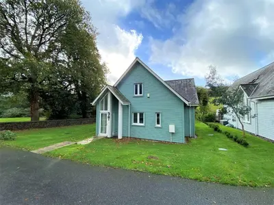a blue house sitting on a grassy yard at Trewhiddle Retreat V23 by Together Travel - Luxury 4-Bedroom Villa in St Austell