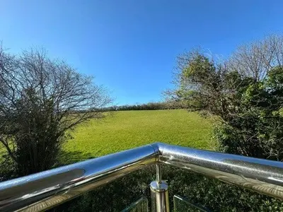 a view of a field and a metal railing at Trewhiddle Retreat V23 by Together Travel - Luxury 4-Bedroom Villa in St Austell