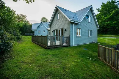 a blue house with a fence in a yard at Trewhiddle Retreat V18 by Together Travel - Luxury 4-Bedroom Villa in St Austell