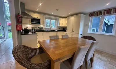 a kitchen with a wooden table and chairs at Trewhiddle Retreat V18 by Together Travel - Luxury 4-Bedroom Villa in St Austell