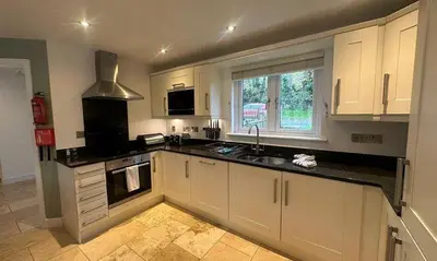 a kitchen with white cabinets and a sink and a window at Trewhiddle Retreat V18 by Together Travel - Luxury 4-Bedroom Villa in St Austell