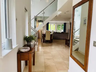a hallway with a staircase and a table with a mirror at Trewhiddle Retreat V20 by Together Travel - Luxury 3-Bedroom Villa in St Austell