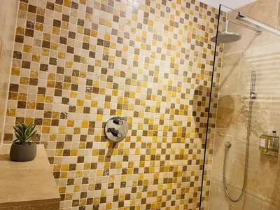 a bathroom with a shower with yellow and brown tiles at Trewhiddle Retreat V20 by Together Travel - Luxury 3-Bedroom Villa in St Austell