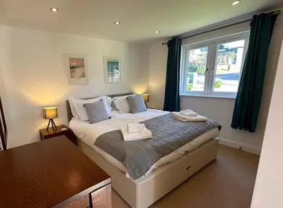 a bedroom with a large bed with a window at Trewhiddle Retreat V20 by Together Travel - Luxury 3-Bedroom Villa in St Austell