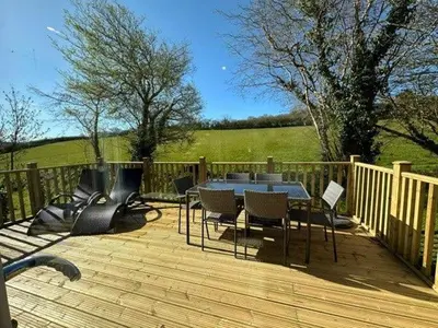 a patio with a table and chairs on a wooden deck at Trewhiddle Retreat V20 by Together Travel - Luxury 3-Bedroom Villa in St Austell