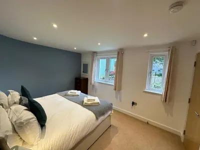 a bedroom with a bed and two windows at Trewhiddle Retreat V17 by Together Travel - Luxury 4-Bedroom Villa in St Austell