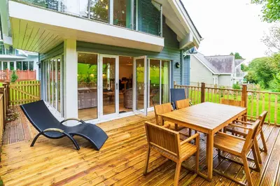 a wooden deck with a wooden table and chairs at Trewhiddle Retreat V17 by Together Travel - Luxury 4-Bedroom Villa in St Austell