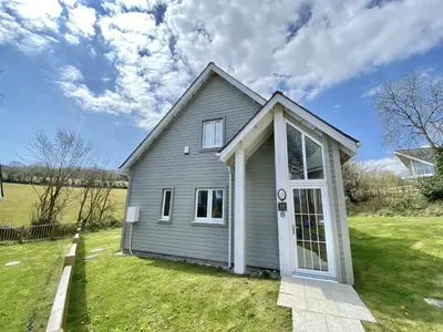 a gray house with a white door on a yard at Trewhiddle Retreat V17 by Together Travel - Luxury 4-Bedroom Villa in St Austell
