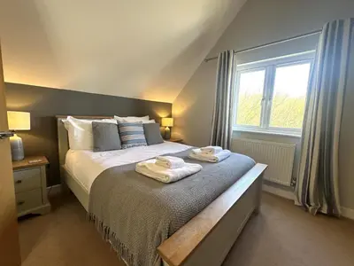 a bedroom with a bed with towels on it at Trewhiddle Retreat V14 by Together Travel - Luxury 4-Bedroom Villa in St Austell