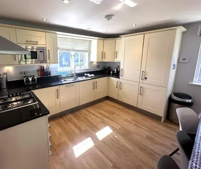 a kitchen with white cabinets and a wooden floor at Trewhiddle Retreat V14 by Together Travel - Luxury 4-Bedroom Villa in St Austell