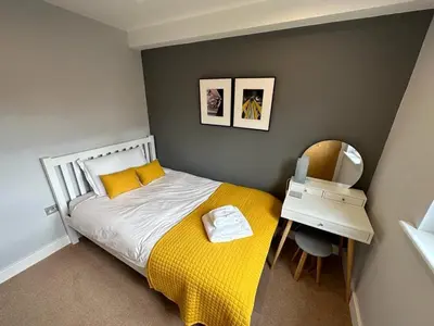 a bedroom with a bed with a yellow blanket and a mirror at Trewhiddle Retreat V14 by Together Travel - Luxury 4-Bedroom Villa in St Austell